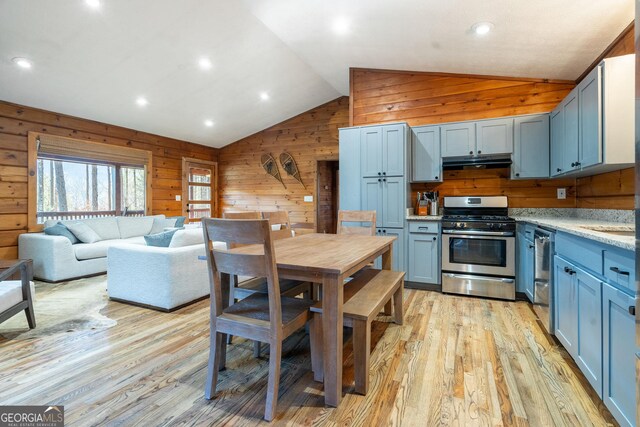 kitchen with light stone countertops, light wood-type flooring, stainless steel appliances, sink, and vaulted ceiling