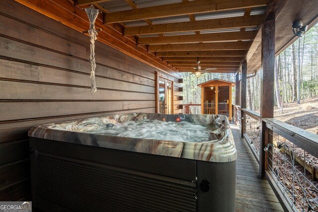 bedroom featuring ceiling fan, ensuite bath, and wooden walls