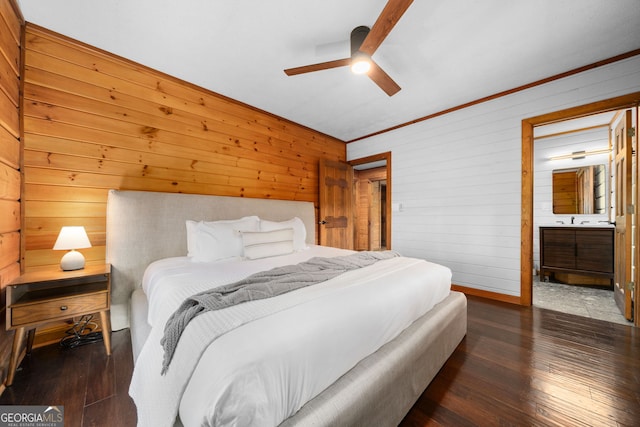 bedroom with a ceiling fan, wooden walls, ensuite bath, and hardwood / wood-style floors