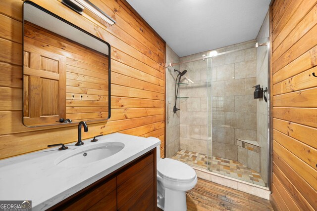 bathroom featuring wood walls, vanity, toilet, and a stall shower