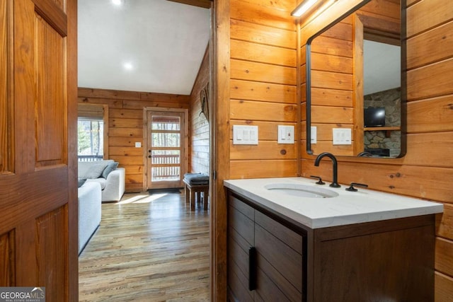 bathroom with vanity, lofted ceiling, hardwood / wood-style flooring, and wooden walls