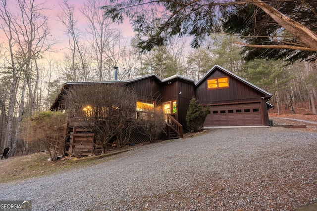 rustic home featuring a garage and gravel driveway