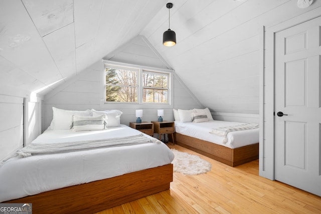 bedroom with lofted ceiling, wood walls, and hardwood / wood-style flooring