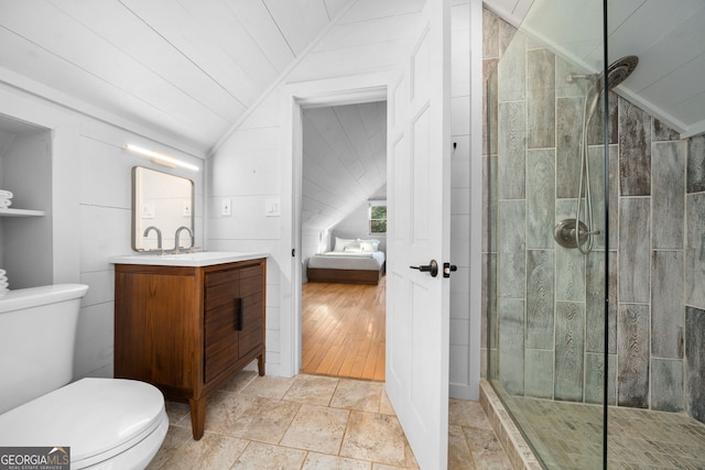 full bathroom featuring vaulted ceiling, a tile shower, toilet, and vanity