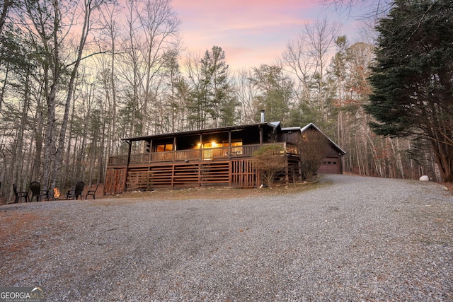 chalet / cabin with a garage, driveway, and a wooden deck