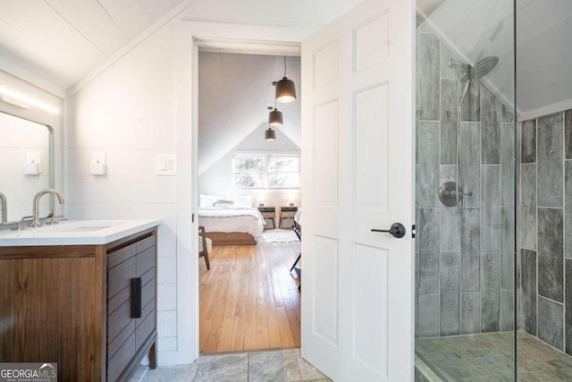 bathroom featuring a tile shower, vanity, and lofted ceiling