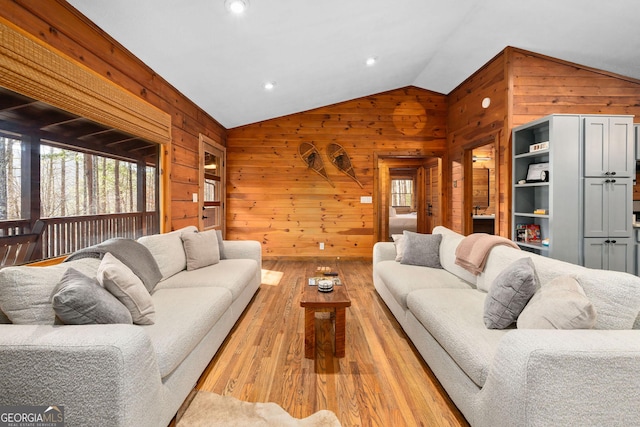 living area featuring vaulted ceiling, light wood finished floors, and wood walls