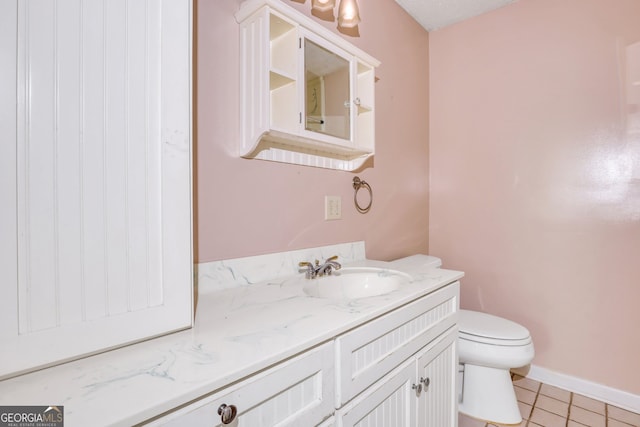 bathroom with toilet, vanity, and tile patterned floors