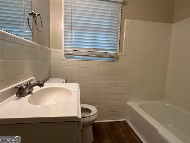 bathroom featuring hardwood / wood-style floors, vanity, a bath, and tile walls