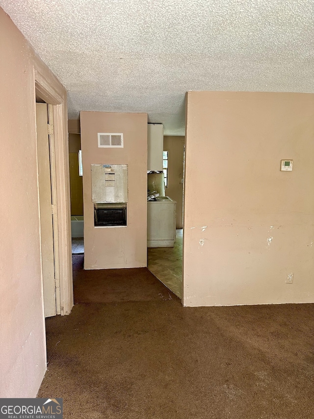 interior space featuring washer / clothes dryer, a textured ceiling, and dark carpet