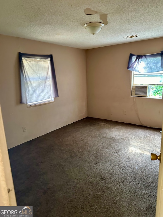 carpeted spare room featuring a textured ceiling and cooling unit