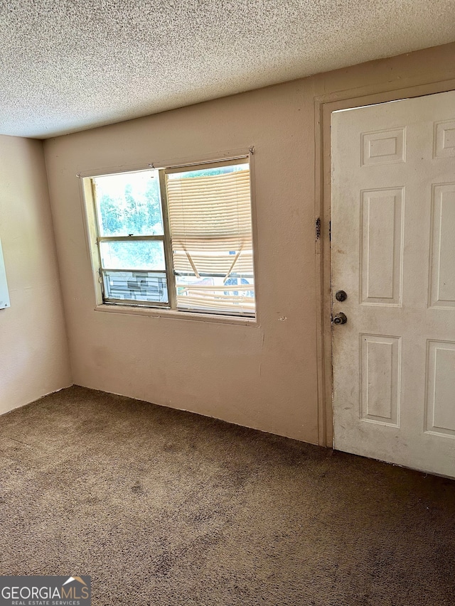 carpeted spare room featuring a textured ceiling