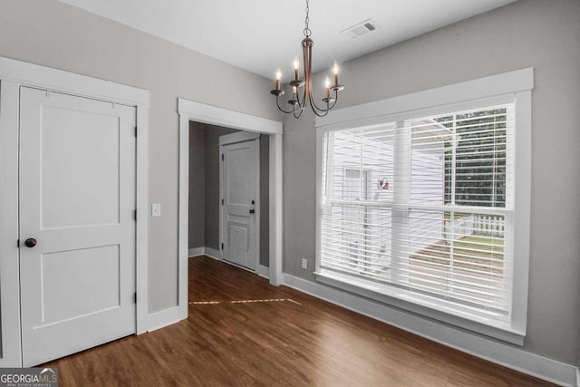 spare room featuring dark wood-type flooring and a chandelier