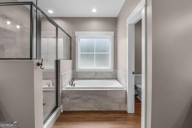 bathroom with toilet, plus walk in shower, and hardwood / wood-style flooring