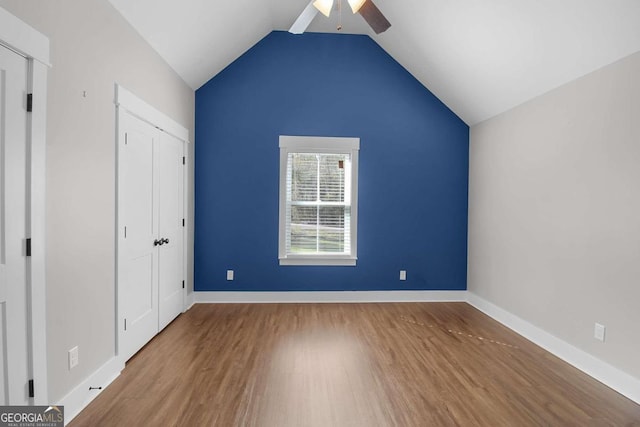 unfurnished bedroom with ceiling fan, wood-type flooring, a closet, and vaulted ceiling