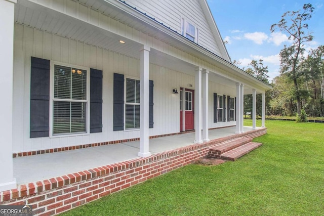 entrance to property featuring a porch and a lawn