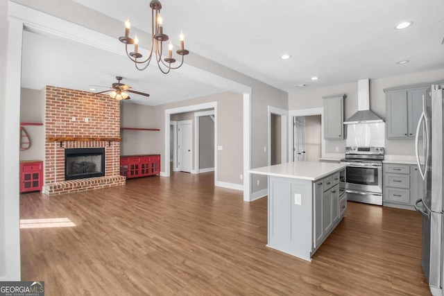 kitchen with gray cabinets, stainless steel appliances, wall chimney exhaust hood, and a kitchen island