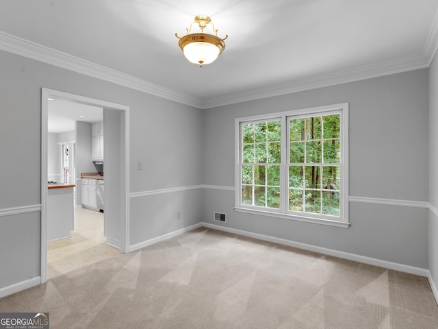 spare room featuring baseboards, crown molding, visible vents, and light colored carpet