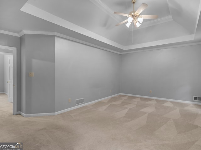 empty room with light carpet, visible vents, a raised ceiling, and crown molding