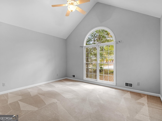 empty room featuring baseboards, high vaulted ceiling, visible vents, and light colored carpet