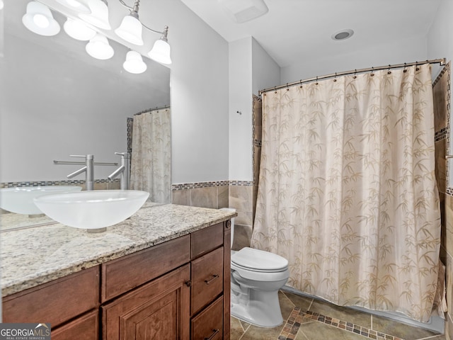 bathroom with toilet, wainscoting, vanity, and tile walls