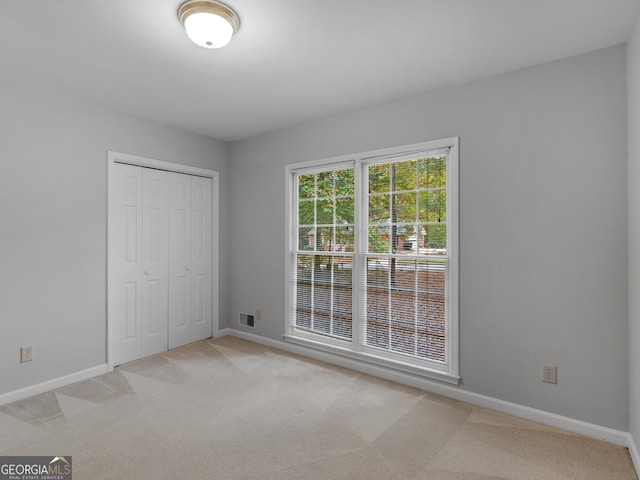 unfurnished bedroom featuring light carpet, visible vents, and baseboards