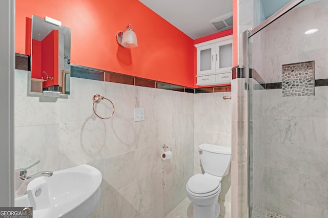 full bathroom with toilet, a stall shower, a sink, and tile walls