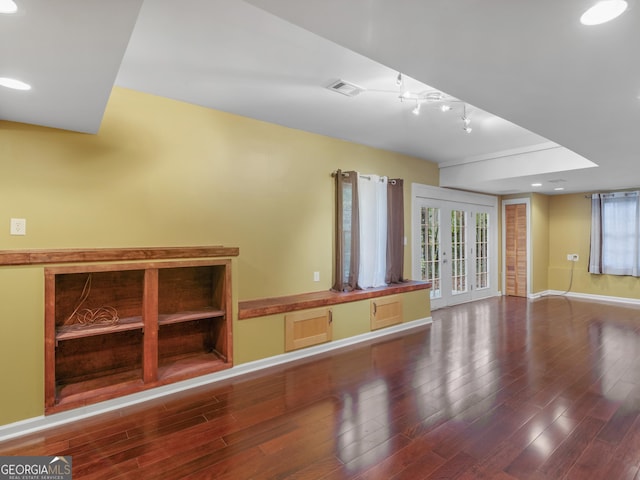 unfurnished living room with baseboards, visible vents, wood finished floors, rail lighting, and french doors