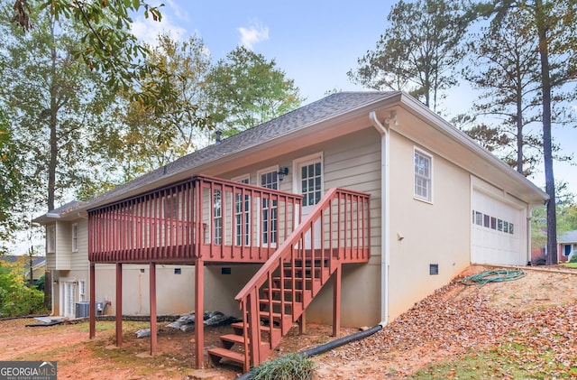 view of side of property with a shingled roof, an attached garage, stairs, a deck, and central AC