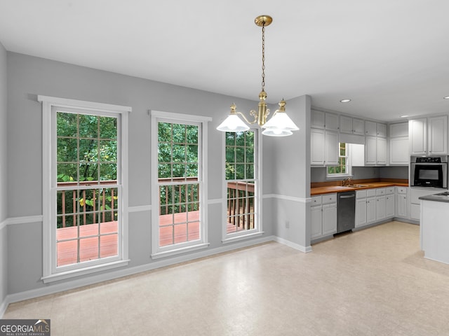 kitchen with stainless steel appliances, butcher block countertops, a wealth of natural light, light floors, and pendant lighting