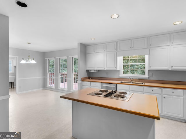 kitchen with a center island, white cabinets, hanging light fixtures, and a sink