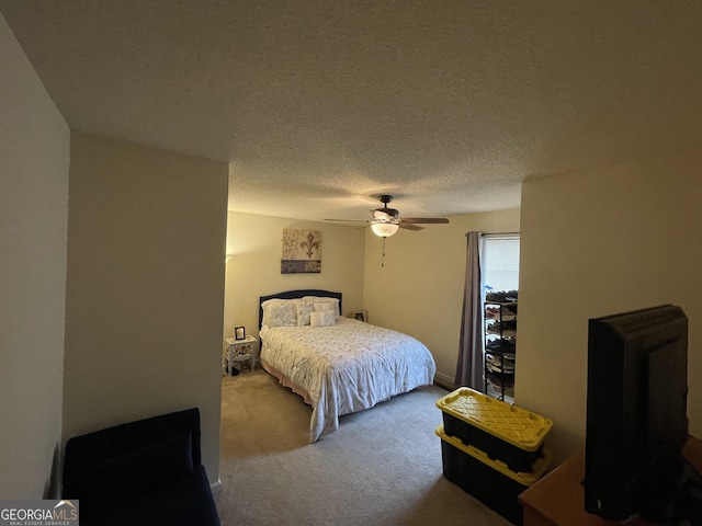 bedroom with ceiling fan, carpet floors, and a textured ceiling