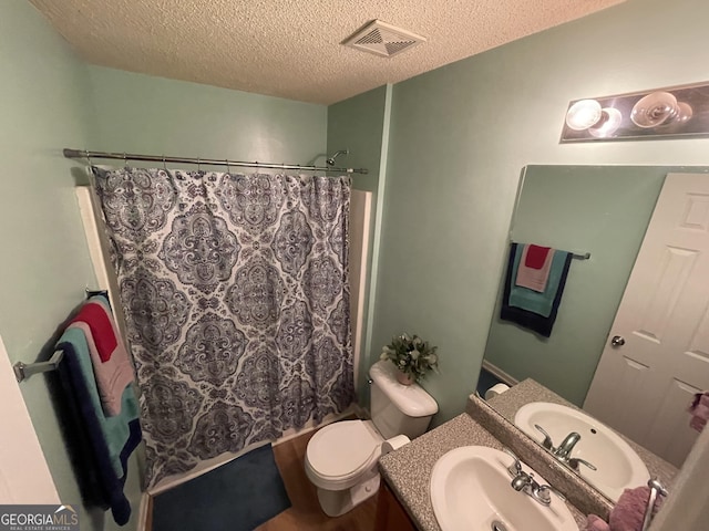 bathroom with vanity, toilet, and a textured ceiling