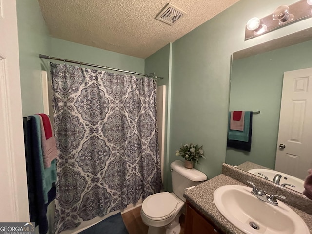 bathroom featuring curtained shower, vanity, a textured ceiling, and toilet