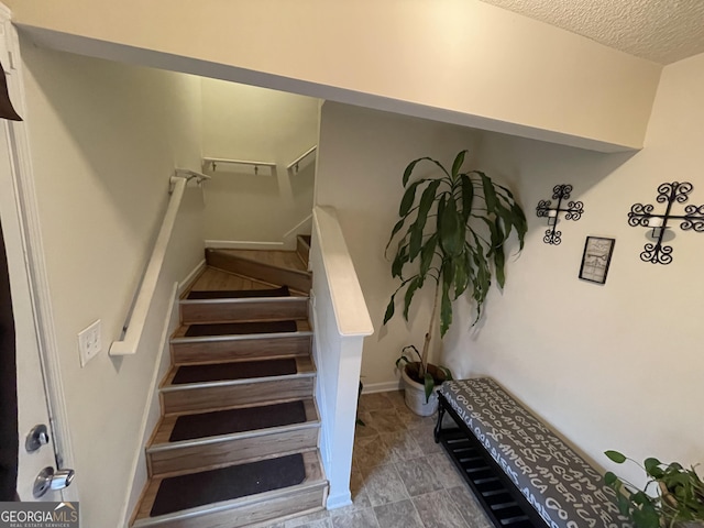 staircase with a textured ceiling