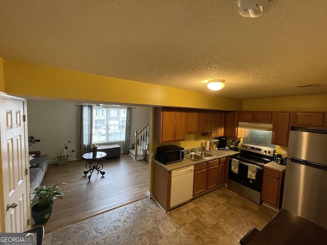 kitchen featuring a textured ceiling, light wood-type flooring, sink, and appliances with stainless steel finishes