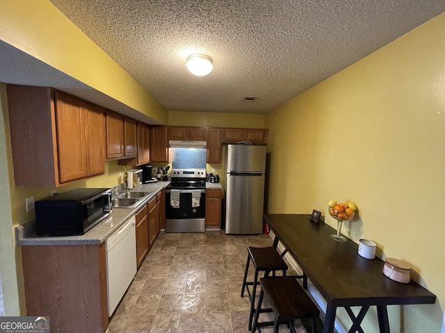 kitchen with a textured ceiling, stainless steel appliances, and sink