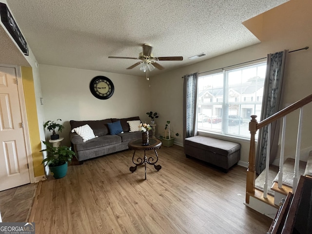 living room featuring ceiling fan, a textured ceiling, and light hardwood / wood-style flooring