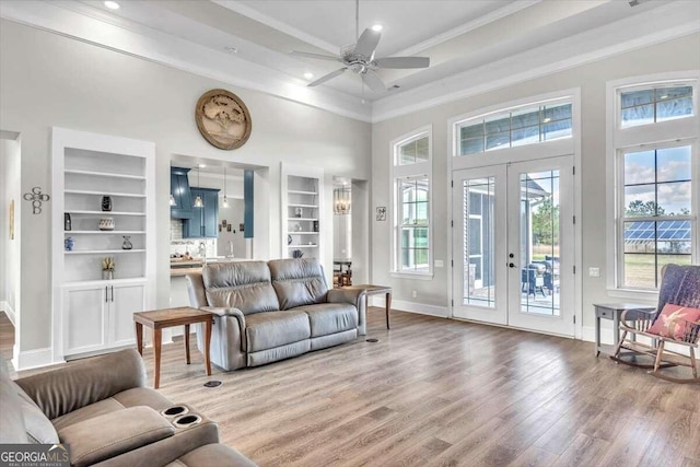 living room with a high ceiling, ceiling fan, hardwood / wood-style floors, crown molding, and french doors