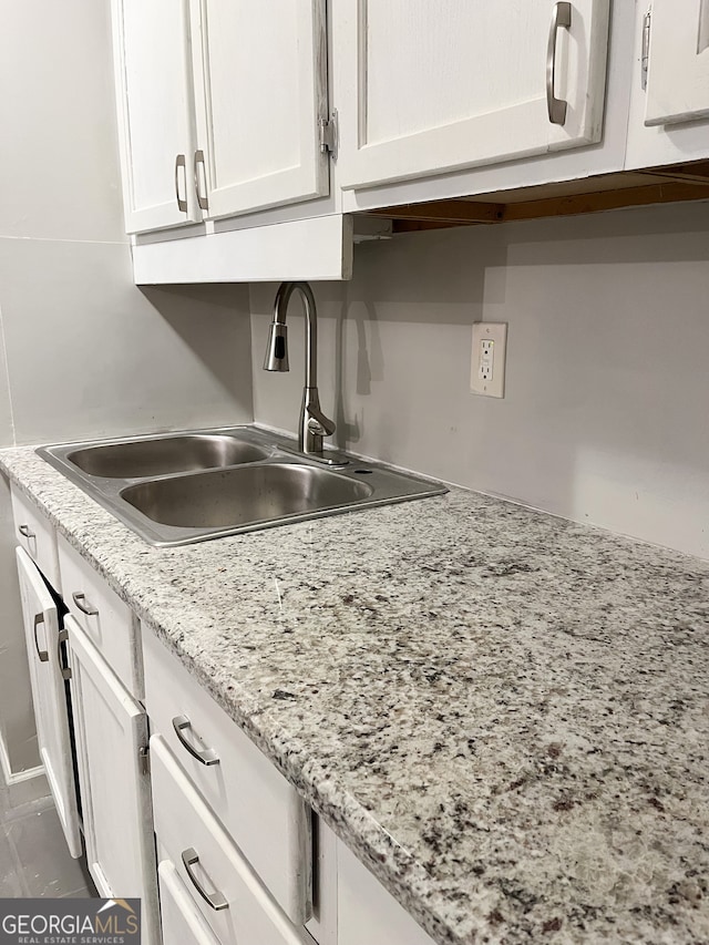 kitchen with white cabinetry, sink, and light stone counters