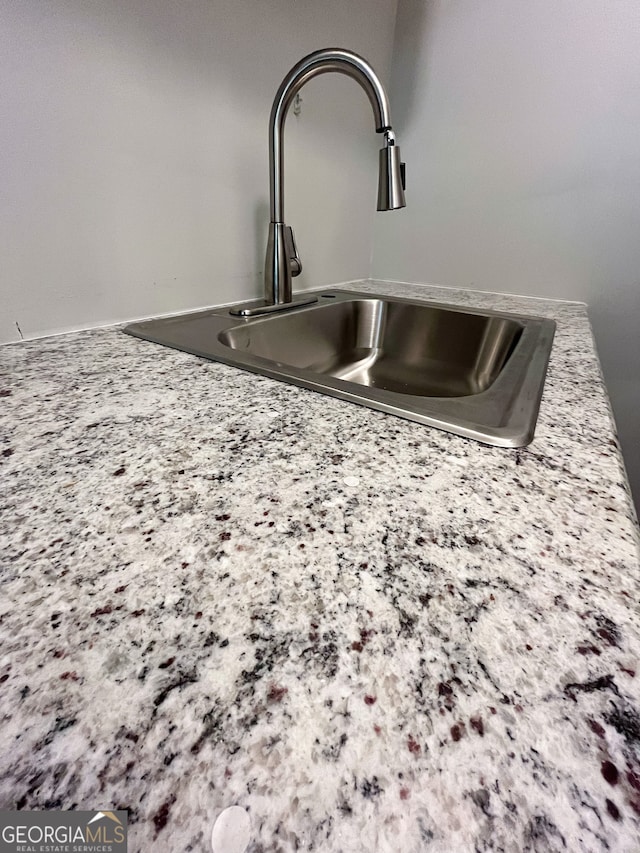 interior details featuring light stone countertops and sink