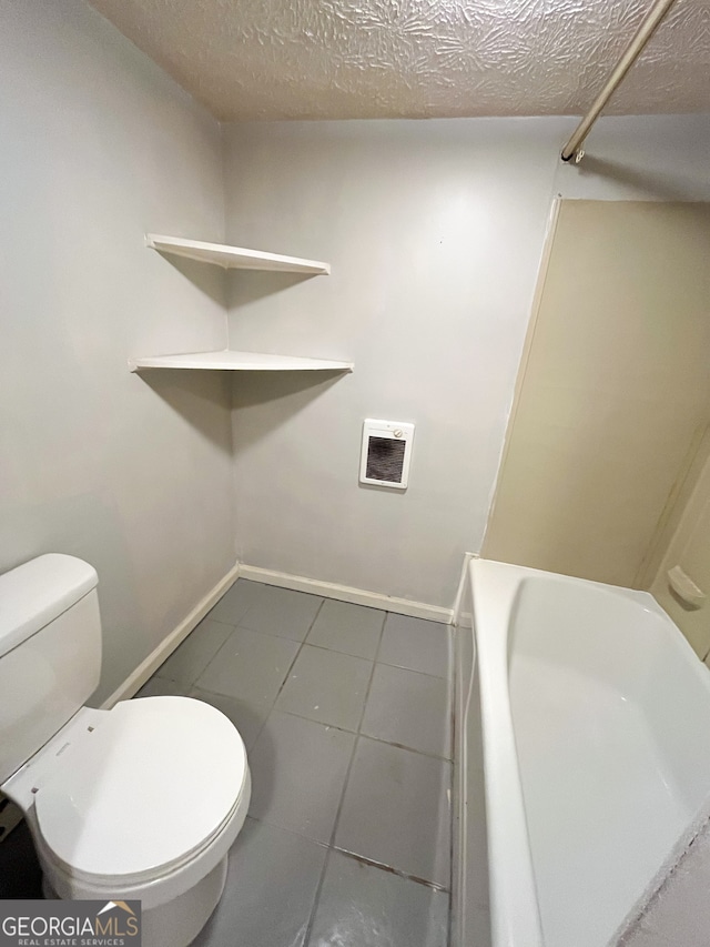 bathroom with toilet, a textured ceiling, and tile patterned floors