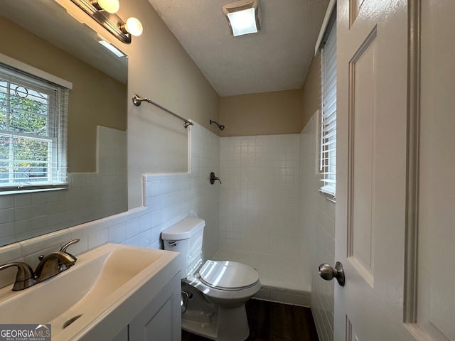 bathroom with vanity, tile walls, a textured ceiling, and a tile shower