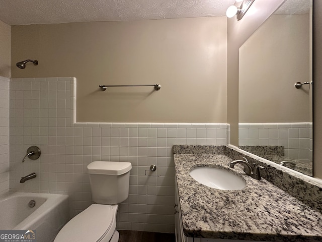 full bathroom with tile walls, vanity, a textured ceiling,  shower combination, and toilet