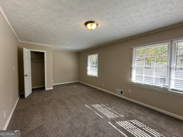 unfurnished bedroom with crown molding, a closet, and dark carpet