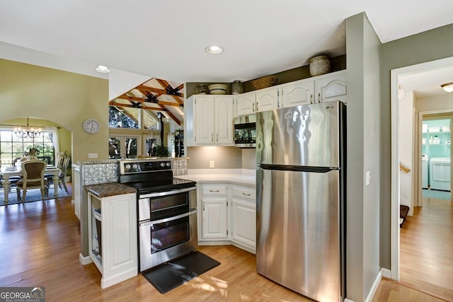 kitchen featuring stainless steel appliances, white cabinetry, a notable chandelier, light hardwood / wood-style floors, and washing machine and dryer