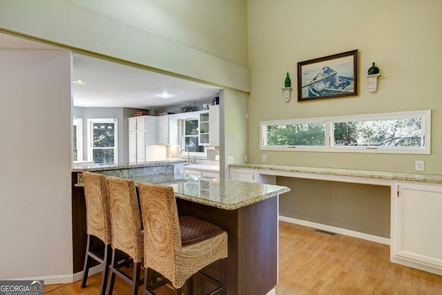 kitchen featuring white cabinets, light wood-type flooring, built in desk, and a breakfast bar