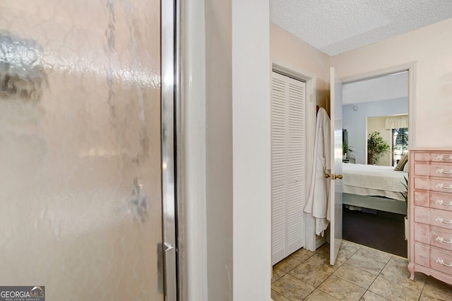 bathroom featuring a shower with door, tile patterned flooring, and a textured ceiling