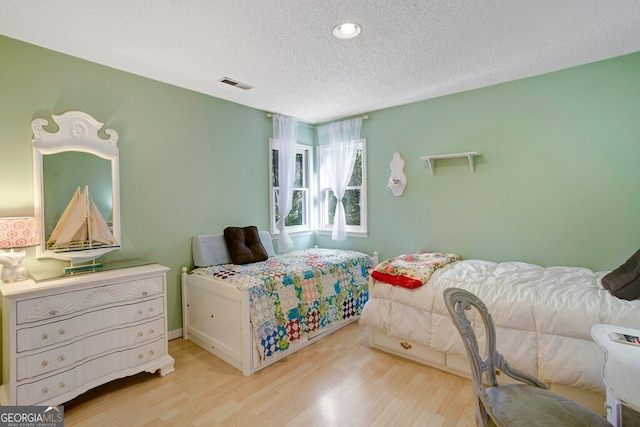 bedroom with a textured ceiling and light hardwood / wood-style flooring