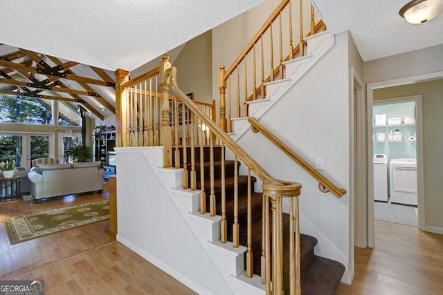 stairway with independent washer and dryer, wood-type flooring, lofted ceiling with beams, and a textured ceiling